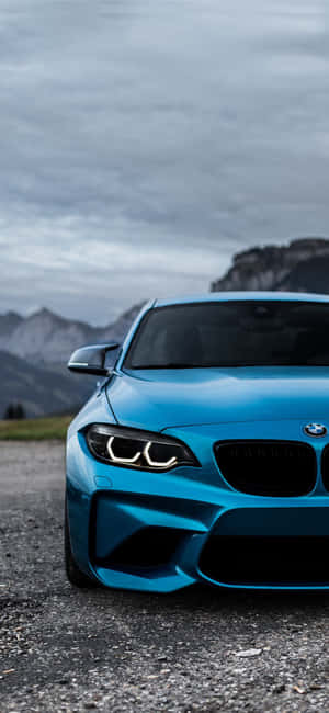 藍色BMW跑車停在碎石上，靠近山脈，天空多雲