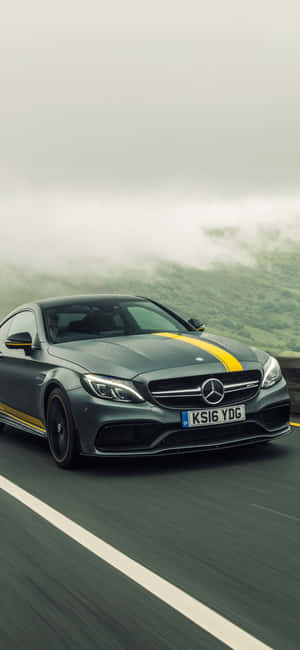 灰色 Mercedes-AMG 帶有黃色條紋在霧氣瀰漫的山路上行駛。