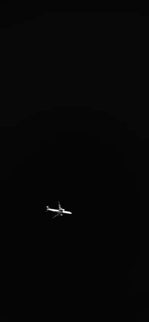 一架飛機獨自在黑色夜空中飛行。 — POCO M7 Plus 壁紙
