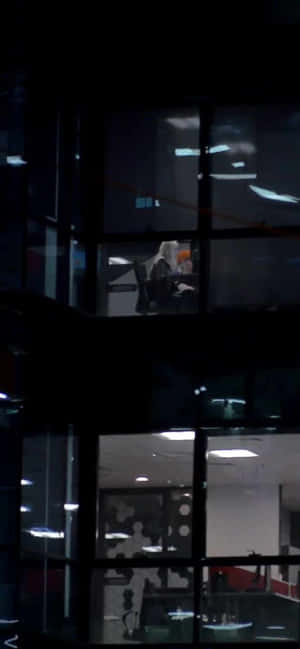 現代辦公大樓的夜景，明亮的窗戶顯示出內部的員工。