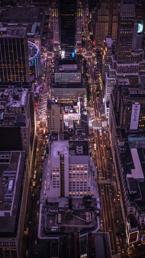 密集城市景觀的夜間鳥瞰圖，街道和建築物燈火通明。 — iPhone 7 壁紙