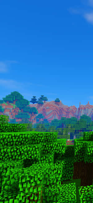 在藍天下，Minecraft遊戲世界中的方塊綠色樹木和紅色山脈。 — OnePlus Ace 壁紙