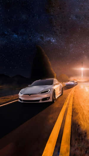 兩輛銀色Tesla在星空下的沙漠公路上夜間行駛。