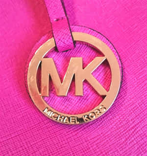 Michael Kors標誌吊飾在粉紅色皮革上的特寫。