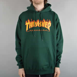 穿著綠色連帽衛衣的人，帶有橙色火焰風格Thrasher Magazine標誌。