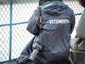 穿著黑色Vetements外套的人，肩上掛著Canon相機。