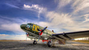 復古軍用飛機停在碎石停機坪上，天空多雲 — 天空景觀 壁紙