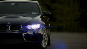 夜間道路上，深藍色BMW跑車亮著明亮的車頭燈。