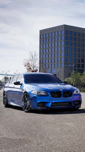 藍色BMW M5停喺一棟現代辦公樓前面，天色多雲。