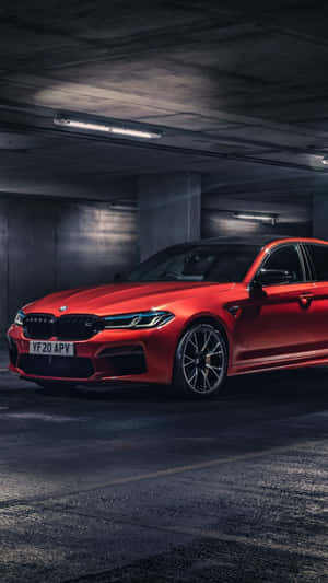 紅色BMW M5停放在光線昏暗的地下停車場，旁邊有混凝土柱。