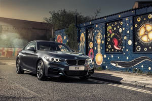 灰色BMW X14停泊在日落時分色彩繽紛的塗鴉牆旁。