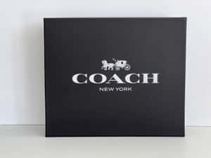 白色表面上的黑色 Coach New York 品牌盒子。