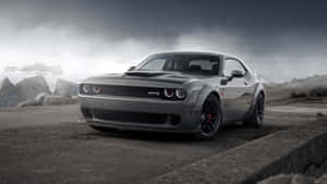 灰色 Dodge Challenger SRT Hellcat 停泊在混凝土邊緣上，暴風雨天空和岩石