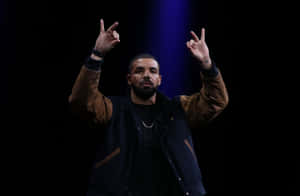 Drake 在藍光下於舞台上做出和平手勢。
