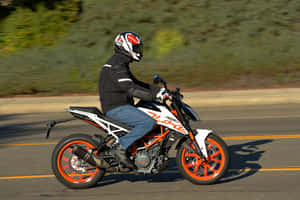 電單車騎士在陽光明媚的道路上騎乘KTM Duke，背景有動態模糊效果。 — 機車 壁紙