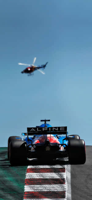 藍色Alpine F1賽車在賽道上奔馳，直升機在上空。