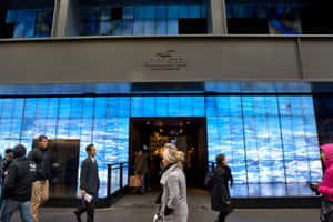 人們夜晚經過一間設有藍色海浪數碼顯示屏的Hollister商店。