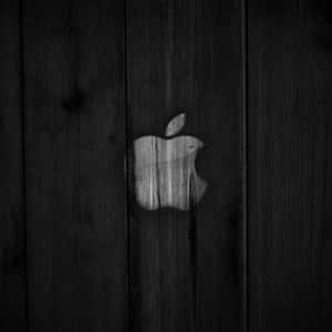Apple標誌蝕刻在深色木質表面上，木紋清晰可見。
