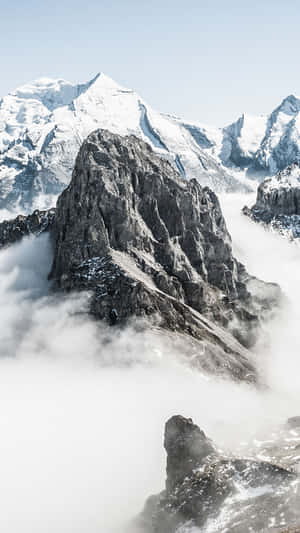 在清澈的藍天下，積雪山峰從雲層中浮現。