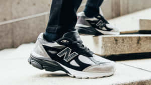 人在混凝土樓梯上穿著黑白New Balance運動鞋。