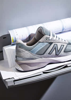 灰色 New Balance 運動鞋放在打印機托盤上，附近有打印好的文件。