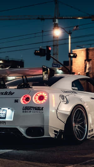 白色改裝日產GT-R，夜晚的城市街道十字路口。