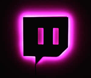 一個發光的粉紅色 Twitch 標誌招牌在黑暗的牆壁上。