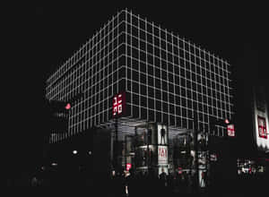 夜晚中一座現代建築，帶有發光的白色網格線和紅色Uniqlo標誌。