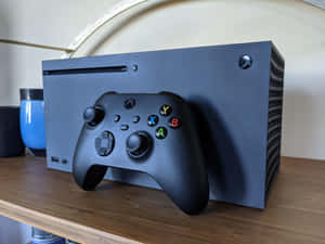黑色 Xbox 主機和手掣放在木架上，附近有藍色杯子。