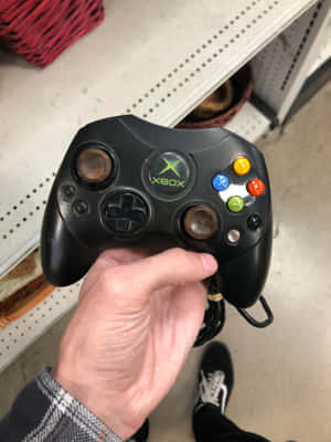 手拿著一個黑色Xbox 360控制器，模擬搖桿已磨損。