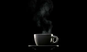 黑色背景下碟子上的冒蒸氣咖啡杯 — 咖啡 壁紙