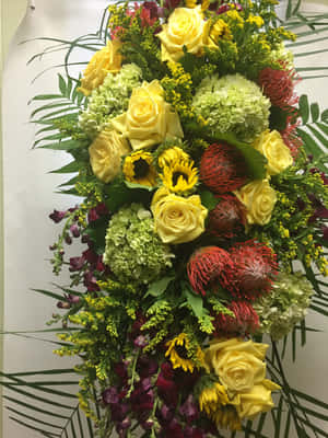 充滿活力的花卉佈置，以黃玫瑰、向日葵和紅色帝王花搭配綠色葉子。 — iPad 壁紙