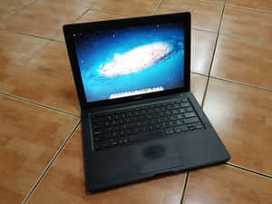 黑色MacBook手提電腦在木地板上顯示星系屏幕
