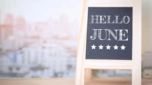 黑板標牌寫著hello june，有五顆星星，放在桌子上，可看到城市景觀。