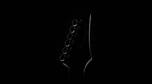 Ibanez 結他頭部在黑色背景上以柔和光線呈現輪廓。