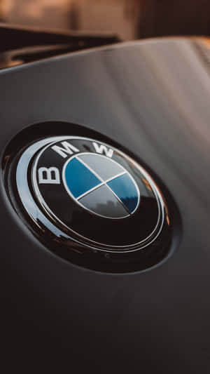 引擎蓋上帶有溫暖光線反射的亮黑色BMW標誌。 — 9:16 壁紙