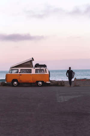 橙色露營車停泊在沙灘上，衝浪者在黃昏時分走向海洋 — Vans GIF 壁紙