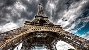 艾菲爾鐵塔在帶有藍色斑塊的戲劇性多雲天空下。 — 巴黎鐵塔 壁紙