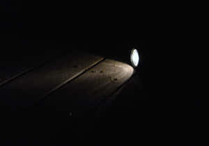手電筒光束在黑暗中照亮木板。 — 省電 壁紙