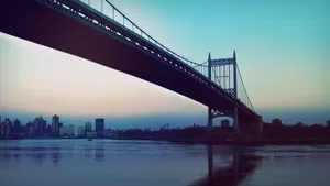 一座大橋橫跨河流,背景是黃昏時分的城市天際線。
