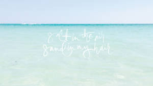 平靜的藍綠色海洋上白色文字寫著 salt in the air sand in my hair。