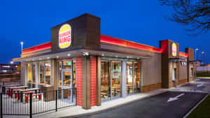 黃昏時分的Burger King快餐店，帶有紅色燈光和戶外餐桌。