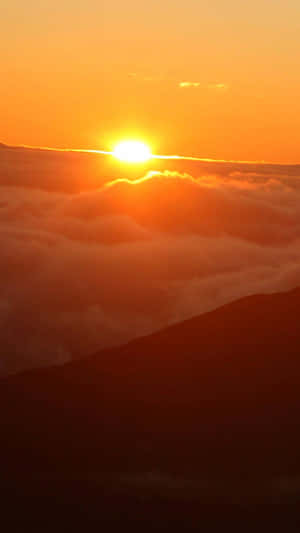太陽在雲海上昇起，下方有山脈輪廓 — 日出 壁紙