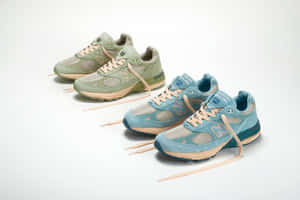 兩對 New Balance 運動鞋，綠色和藍色調，米色鞋帶，白色背景。