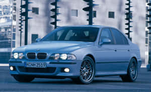 藍色BMW房車停泊在城市街道上，背景有現代建築。