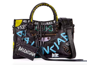 黑色皮革 Balenciaga 手袋，帶有彩色塗鴉文字和流蘇。
