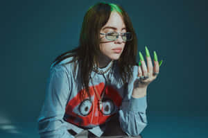 Billie Eilish 在工作室戴著眼鏡和綠色指甲，穿著紅色眼睛襯衫