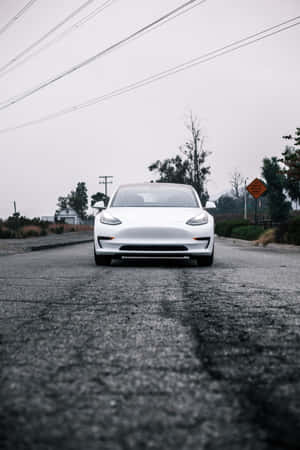灰色天空下潮濕道路上的白色電動車，帶有電線。