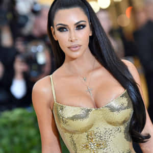 Kim Kardashian 在紅地毯活動中穿著金色連衣裙。