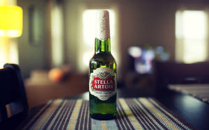 在舒適客廳的條紋桌布上的一個綠色 Stella Artois 啤酒瓶。